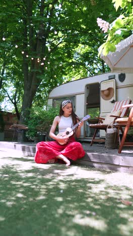 woman playing ukulele in a campervan garden