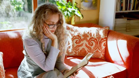 Mature-woman-reading-a-book-in-living-room-4k