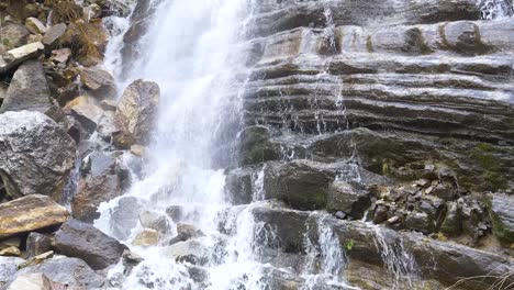 Wasser-Schimmert-Und-Glänzt,-Als-Es-An-Den-Zerklüfteten-Felsen-Unterhalb-Des-Wasserfalls-Herunterfällt