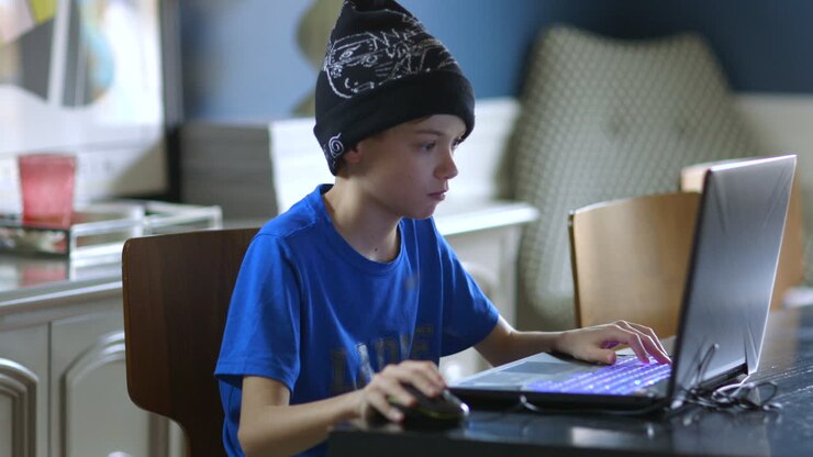 Young boy playing games on a laptop in the dining room medium profile view