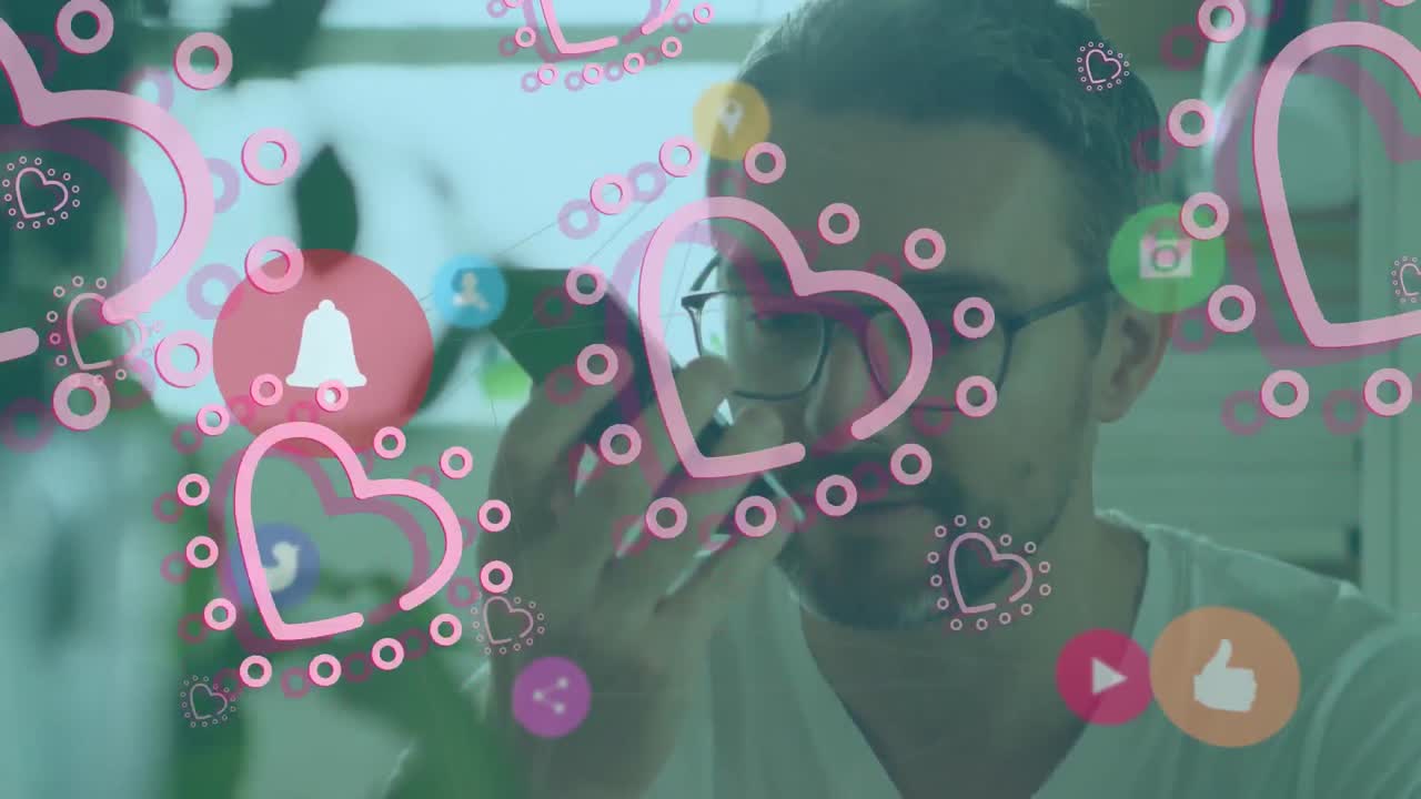 Animation of digital icons and pink hearts floating over caucasian man talking on smartphone at home