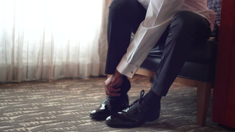 man putting shoe on his right leg during preparation on the wedding day