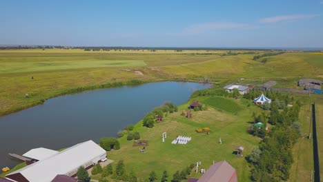 wedding venue on green field at calm lake aerial view