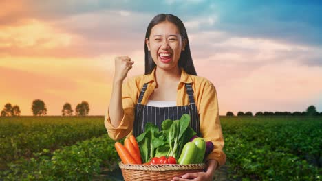 happy asian female farmer with vegetable basket celebrating while standing in field