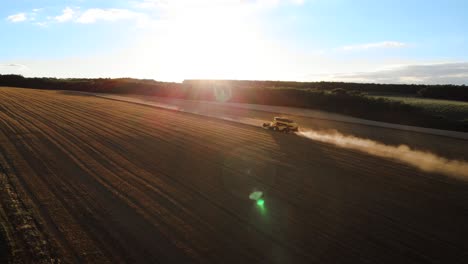 Tiro-De-Dron-De-Una-Cosechadora-Cosechando-Trigo-Dorado-En-Una-Granja-Durante-La-Puesta-De-Sol