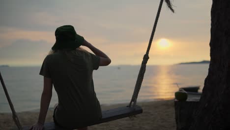 Frauen-Genießen-Den-Sonnenuntergang-Am-Strand,-Während-Sie-Auf-Einer-Seilschaukel-Sitzen