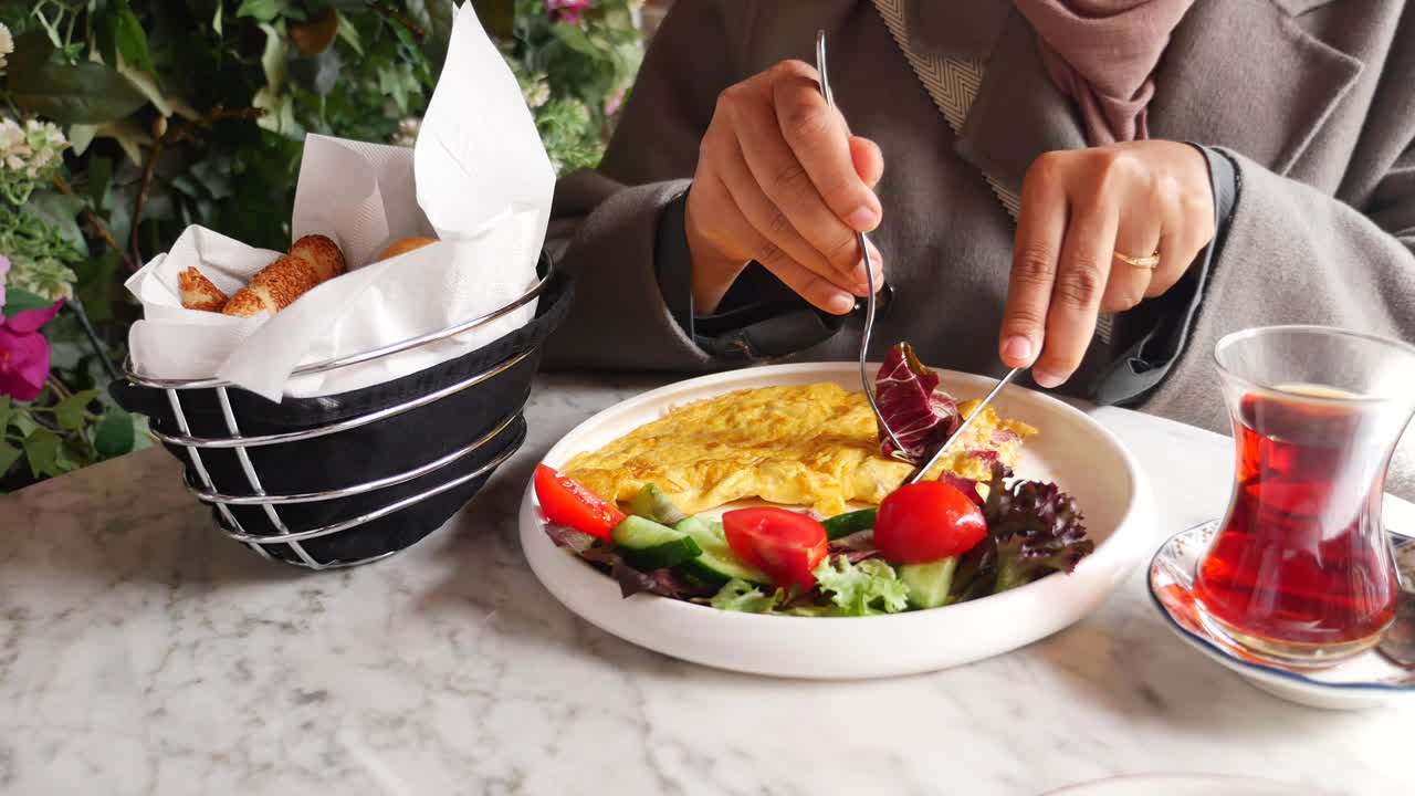 카페에서 오멜, 러드, 차의 맛있는 아침 식사를 즐기는 여자