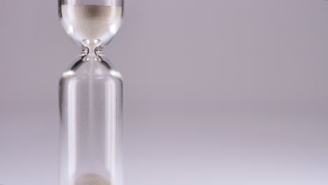 white sand running through bulbs of an hourglass