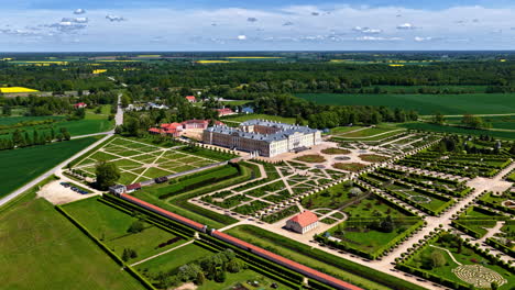 Baroque palace with symmetrical gardens in rural landscape, aerial view in summer