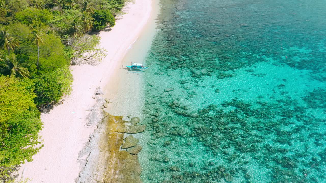 vista aérea. primer barco de banca turístico en la playa de arena tropical. isla de helicóptero, el nido, palawan filipinas. laguna azul con agua clara azulada y hermoso arrecife de coral