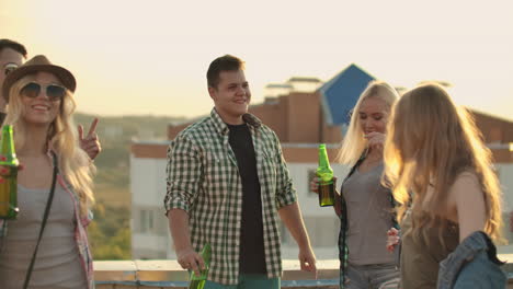 los jóvenes estadounidenses se mueven en un baile en el techo. se divierten sonriendo y bebiendo cerveza.