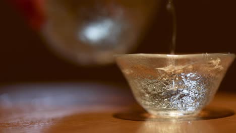 pouring tea into a small glass cup