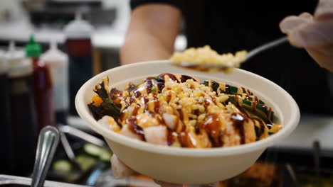 Worker-sprinkles-panko-breadcrumbs-over-traditional-hawaiian-poke-salad-bowl,-slow-motion-close-up-4K