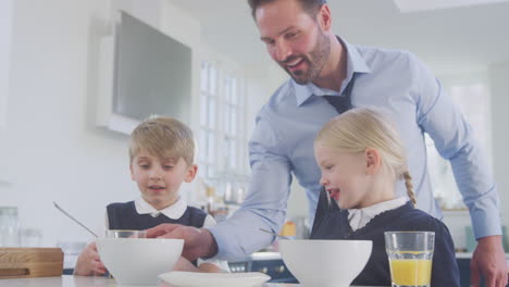 Vater-Serviert-Kindern-In-Schuluniform-Beim-Frühstück-Orangensaft,-Während-Er-Sich-Für-Die-Arbeit-Fertig-Macht