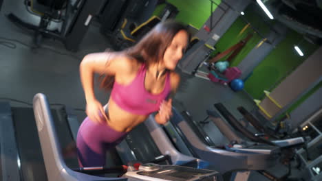right profile of a sporty woman running on a racetrack in fitness center. beautiful woman in pink top and athletic leggings training on a treadmill on the modern gym background.