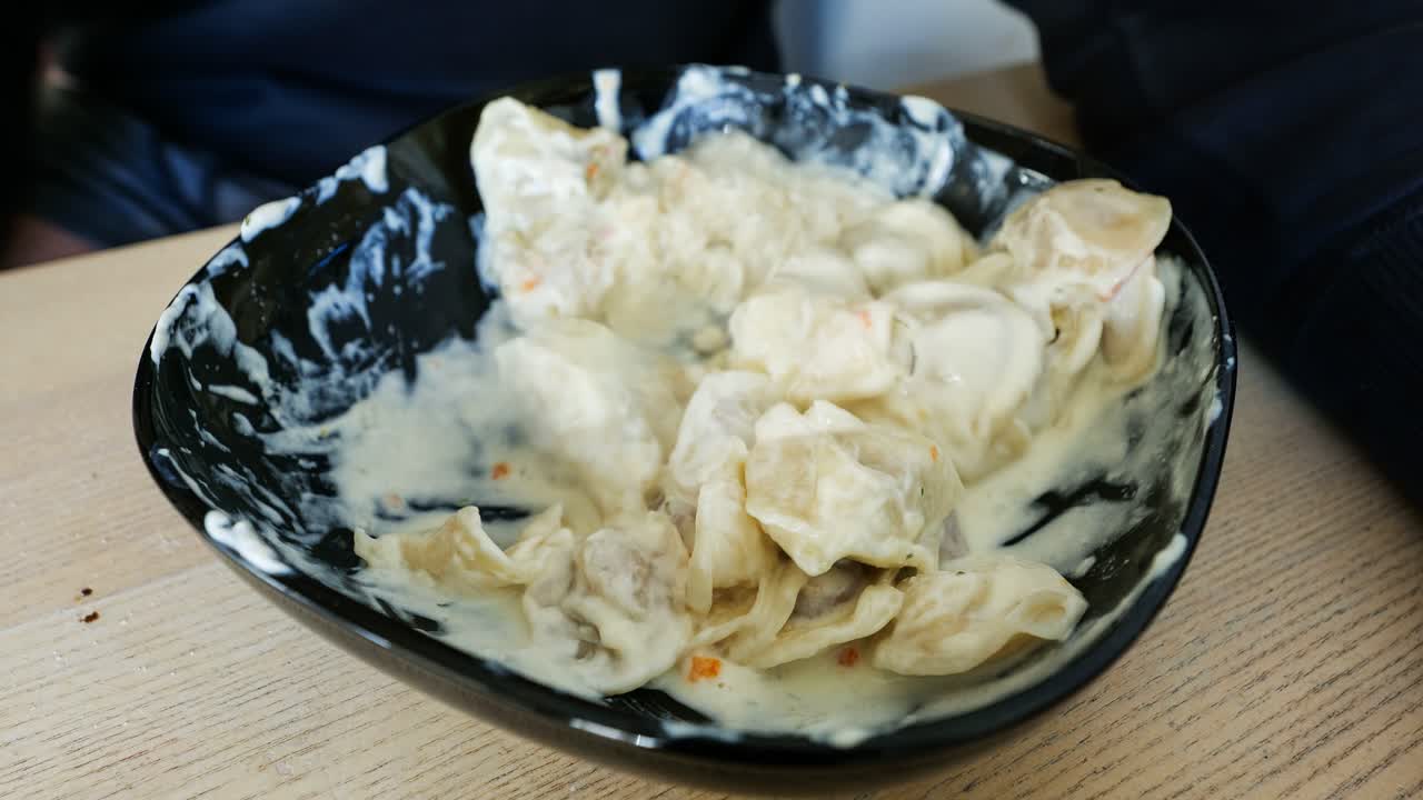 Close-up timelapse of a man eating creamy cheese dumplings in natural daylight