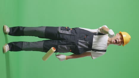 full body of asian man painter wearing safety helmet shouting to camera while standing in the green screen background studio