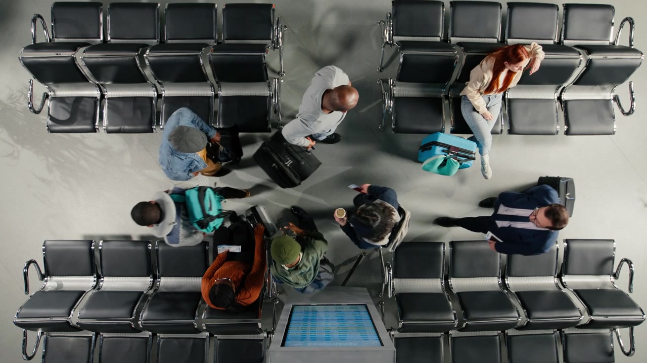 Top down view of people walking in airport terminal, checking departure board
