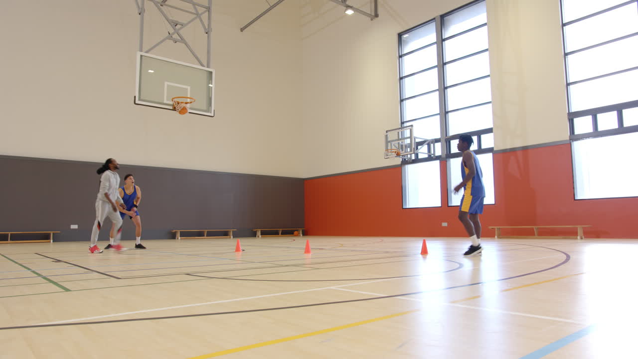 Playing basketball, athletes practicing shooting and passing drills in indoor gym