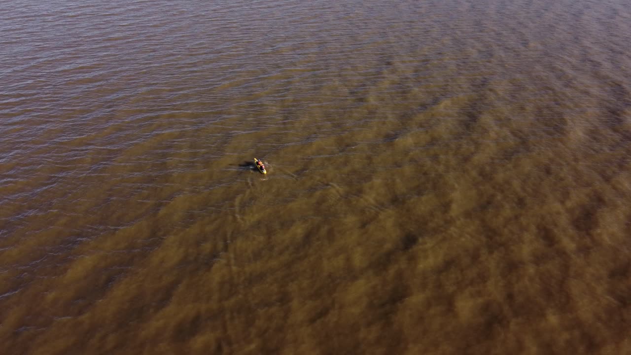 석양에 카약에서 노 젓는 노 젓는 사람 주위를 공전하는 공중 드론