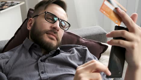 man paying online by bank card at smartphone