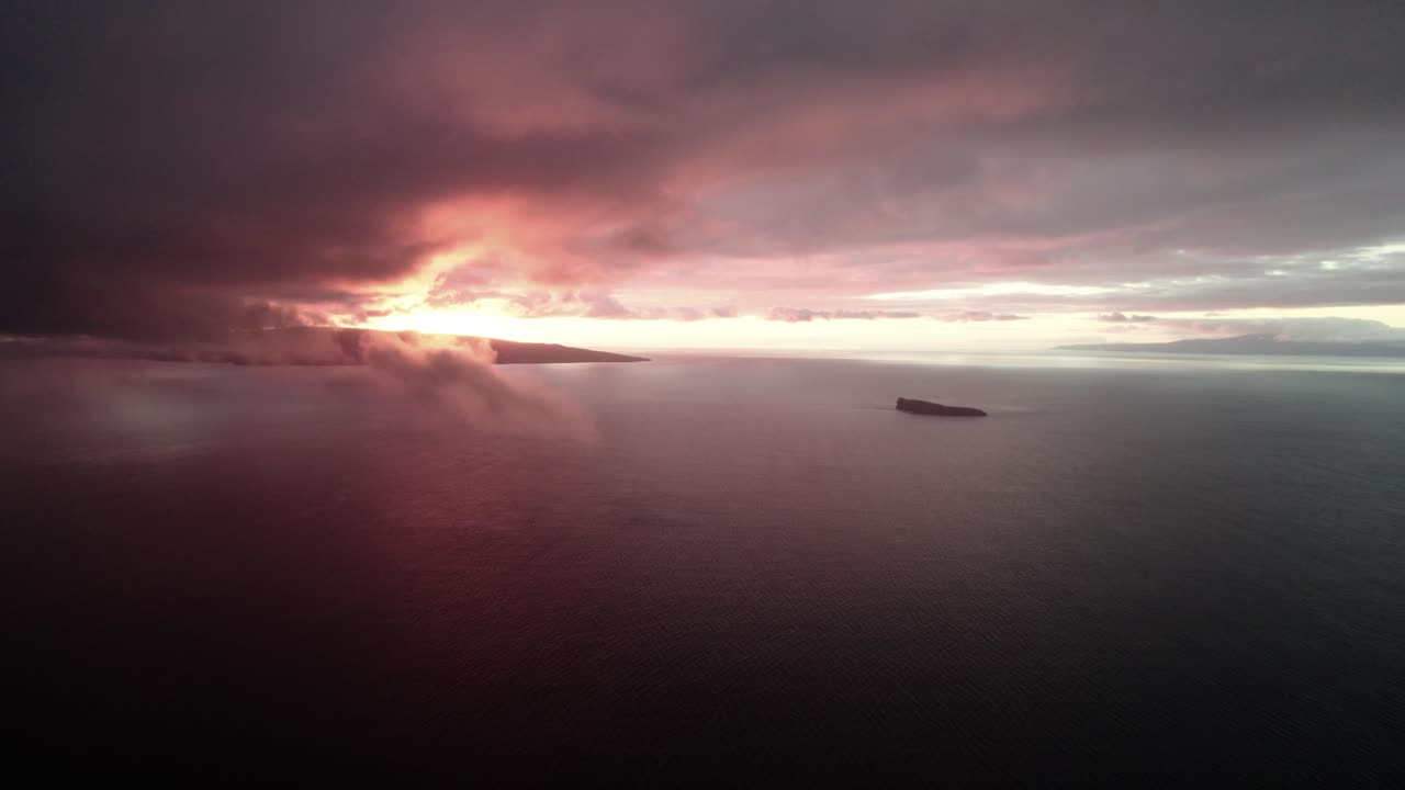 increíble foto aérea lenta a través de las nubes sobre el océano pacífico con el cráter molokini y la isla sagrada de kaho'olawe en la distancia durante la increíble puesta de sol colorida en maui, hawai