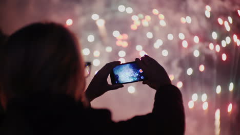 a woman admires the fireworks in the night sky take pictures with your smartphone