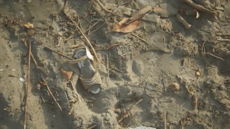 In-a-poignant-slow-motion-shot-with-a-shallow-depth-of-field,-the-Indian-shoreline-reveals-a-disheartening-sight-of-litter-scattered-about,-casting-a-shadow-on-the-natural-beauty