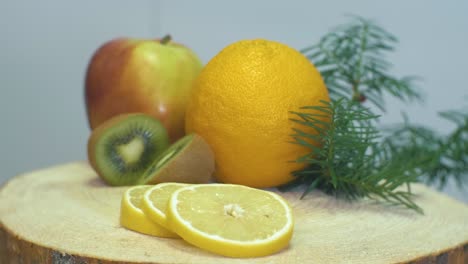 Cierre-El-Video-De-La-Cámara-Haciendo-Zoom-En-Las-Frutas,-Naranja,-Manzana,-Kiwi-Y-Limón-En-Un-Escritorio-De-Madera-Cambiando-El-Enfoque-De-Limón-A-Kiwi-Y-Manzana