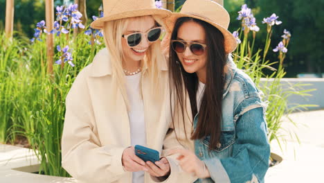 two young women looking at a phone in a park