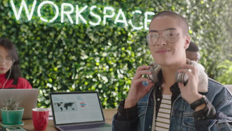 portrait happy mixed race businessman student smiling enjoying successful career in trendy modern office using laptop computer listening to music wearing glasses