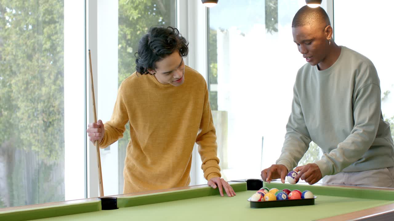 After friend's nod, diverse male friends arranging billiard balls on pool table to play at home