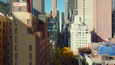 Forwards-fly-between-high-rise-buildings-in-city.-Autumn-colour-trees.-Manhattan,-New-York-City,-USA