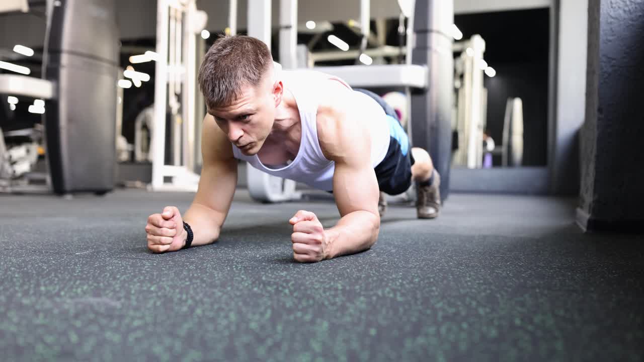 Hombre en forma hace una plancha para fortalecer el cuerpo en el gimnasio