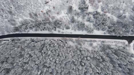 Mountain-forest-road-in-snowy-winter-landscape,-aerial-bird's-eye-view