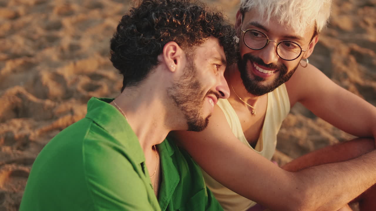 Happy Gay Couple Embracing and Smiling on Beach at Sunset