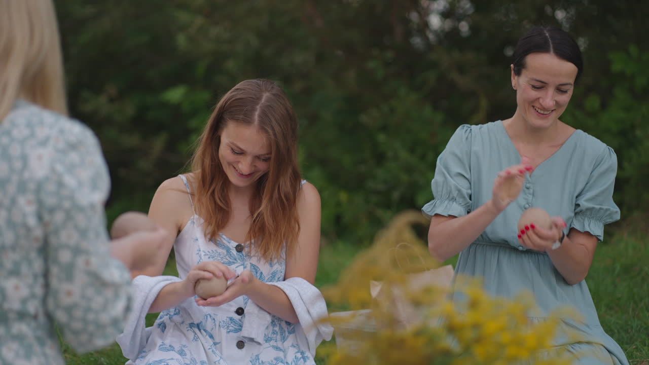 한 무리의 젊은 여성들이 공원에서 자연에서 점토로 조각을 하고 있습니다. 소녀들은 함께 공예 창의성에 종사하고 있습니다. 소통하고, 웃고, 이야기하고, 그 과정을 즐기고 있습니다.