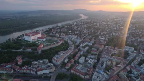 Epic-aerial-view-of-Bratislava-cityscape-with-castle-on-top-of-hill-at-sunset