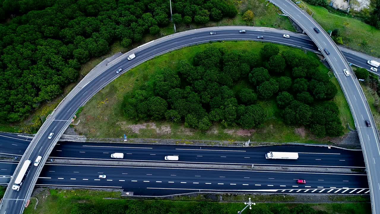 프랑스의 고속도로 교차로 위의 공중 전망: 도로 주변의 집과 풀, 도로에서 운전하는 자동차와 트럭.