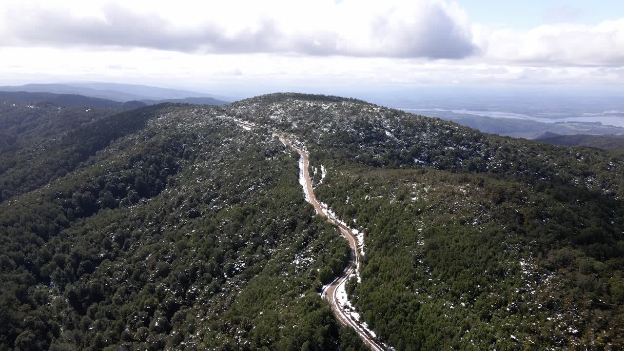 칠레 온콜 공원에서 찍은 배경에 호수가 있는 눈 덮인 숲 한가운데 있는 흙길의 공중 풍경