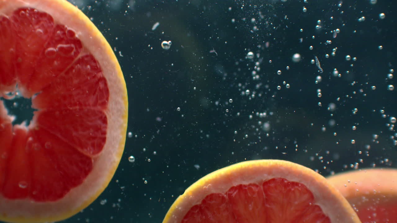3 Grapefruit rings Underwater with air bubbles and in slow motion. Fresh and juicy healthy vegetarian