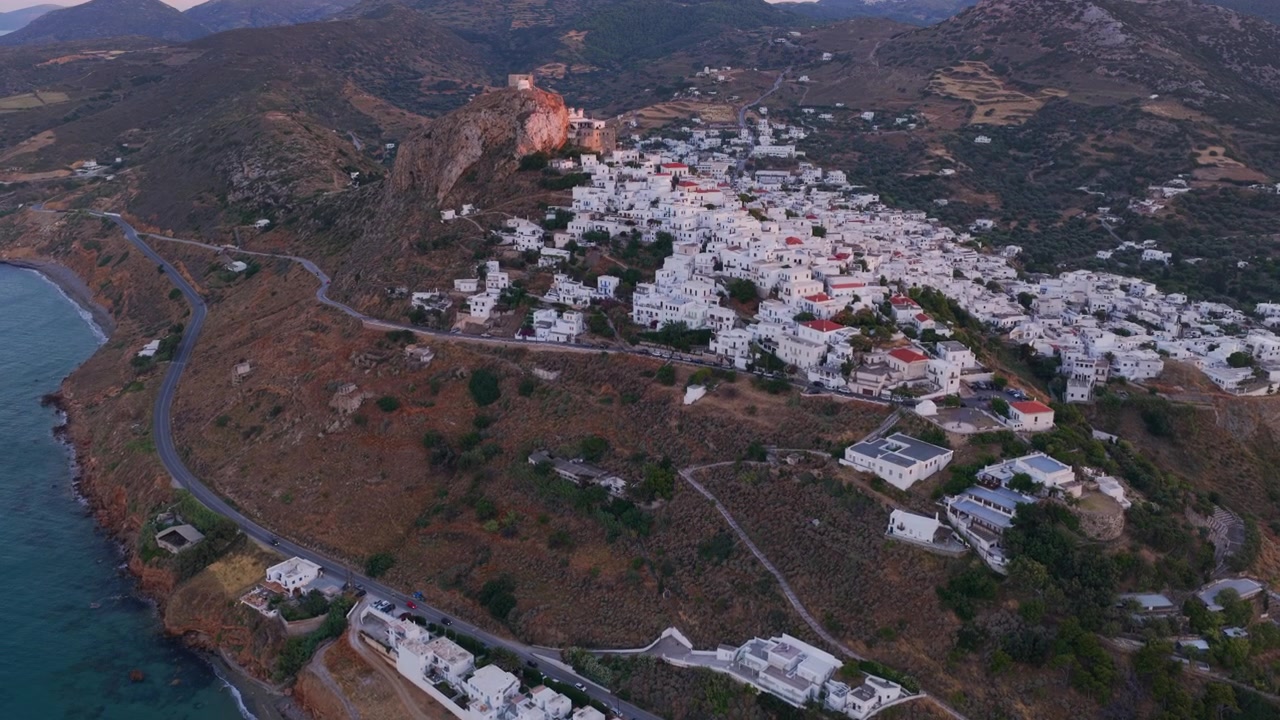 Luftfoto af de hvidkalkede huse i Chora landsby, bygget på en bakke ved Det Ægæiske Hav på Skyros-øen, Grækenland, under en naturskøn og farverig solnedgang, der fremhæver kystlinjen