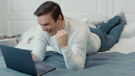 smiling business man making yes gesture in front of computer screen at home