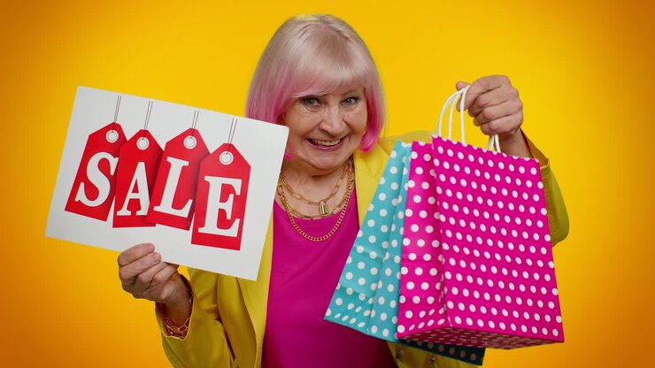 Anziana nonna che mostra un banner con la scritta "Saldi", pubblicizzando sconti e prezzi bassi per le festività.