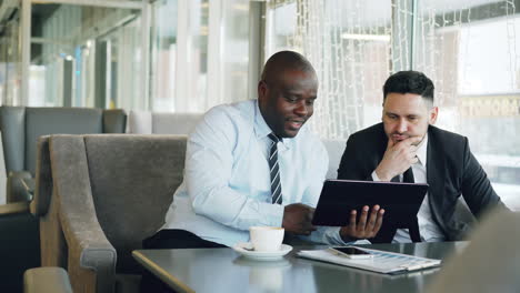 business partners discussing project on digital tablet in a cafe