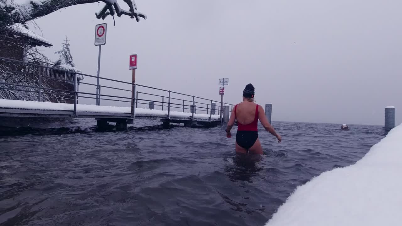mujer entrando en un lago helado en invierno para un baño de hielo