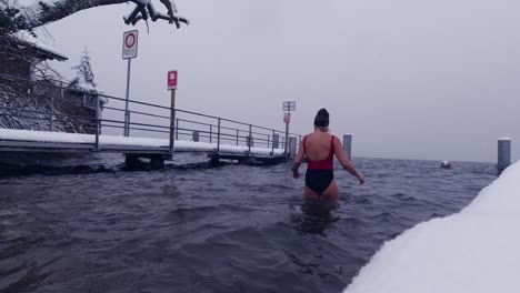 Woman-entering-ice-cold-lake-in-winter-for-an-ice-bath