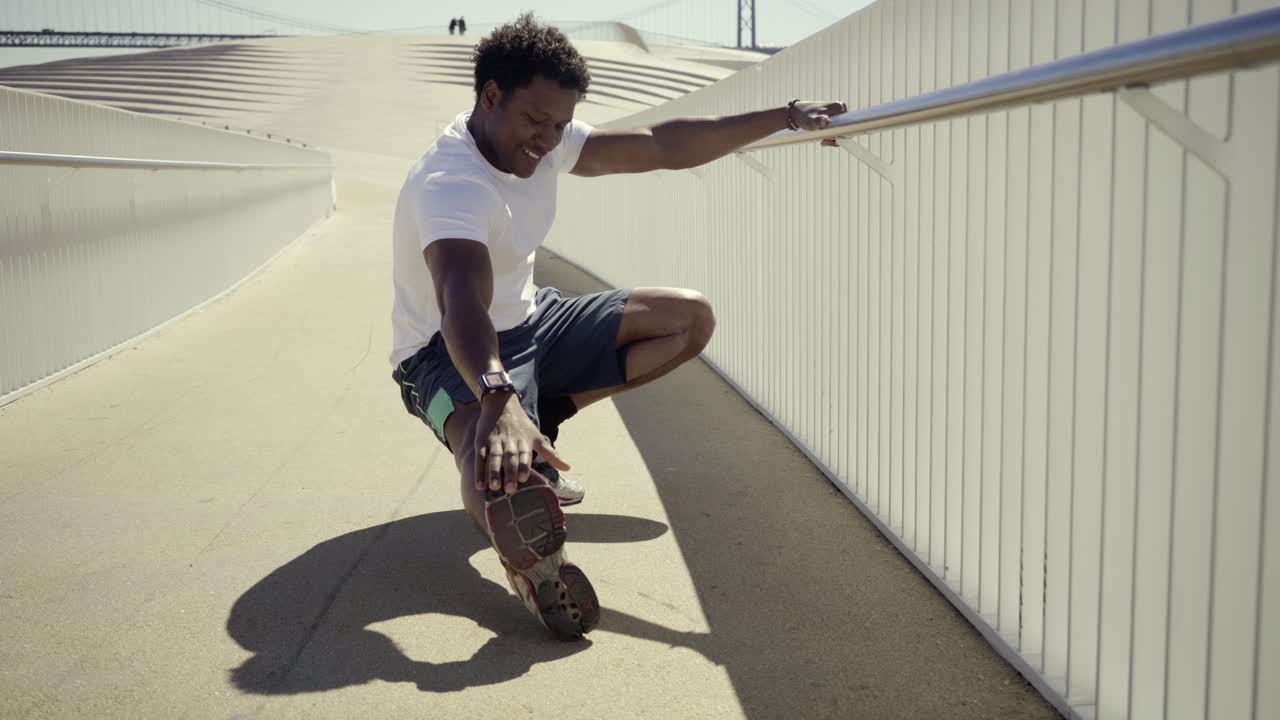 Uomo afroamericano sorridente che allunga le gambe prima dell'allenamento