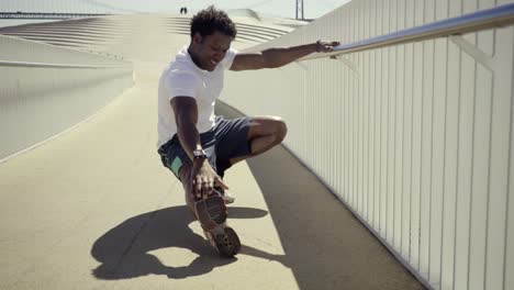 Smiling-African-American-man-stretching-legs-before-workout