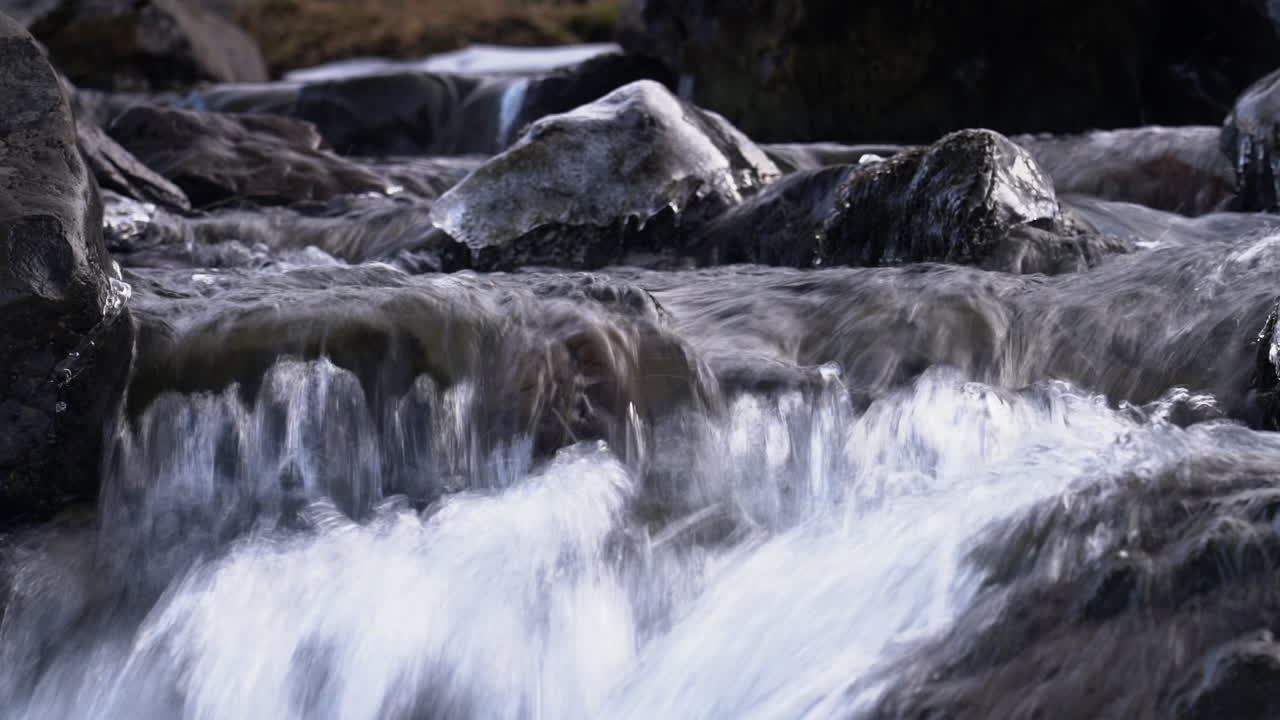 Crystalline Water Flowing Over Frosted Rocks On The River Of Grundarfoss Waterfalls In Western Iceland